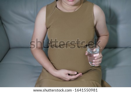 asian pregnant woman while drinking water, Young woman  in livingroom.
