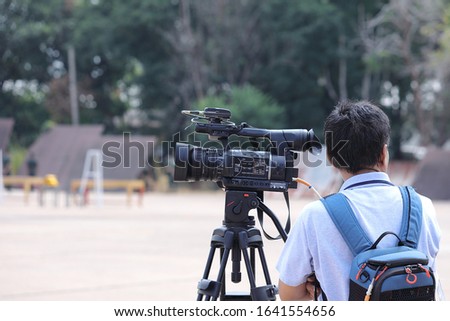 Cameraman.The person who set up the camera shoots video outdoors. Royalty-Free Stock Photo #1641554656