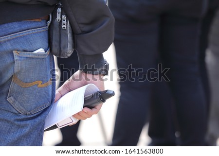 A reporter with a microphone standing back Royalty-Free Stock Photo #1641563800