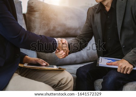 Two confident business man shaking hands during a meeting in the office, success, dealing, greeting and partner in sun light
