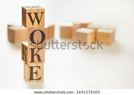 Four wooden cubes arranged in stack with word WOKE (stands for Wisdom Opportunity Knowledge and Empowerment) on them, space for text / image at down right corner