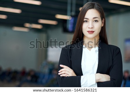 Smiling asian business woman in modern office or meeting room. crossed arms.