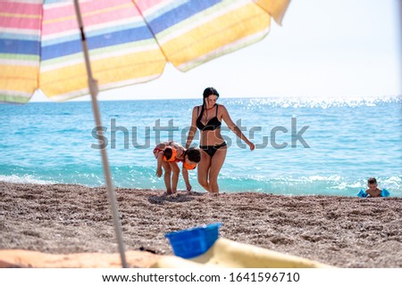 Mother and daughter enjoying by the water on the pebbly beach