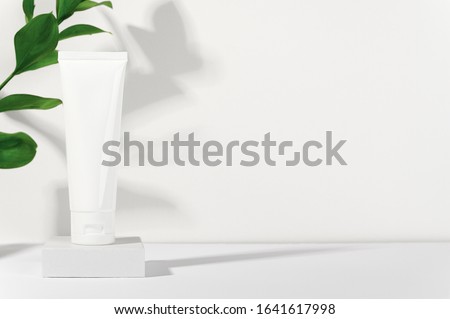 White cosmetic products tube on stand. Blank plastic container for cream, lotion, toothpaste, nourishing or moisturizing mask. Eco-friendly, organic cosmetology concept. Copy space in right side Royalty-Free Stock Photo #1641617998