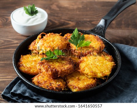 Potatoes pancakes latkes, flapjacks, hash brown or potato vada with white greek yoghurt or sour cream on brown wooden table. Copy space for text. Royalty-Free Stock Photo #1641650557