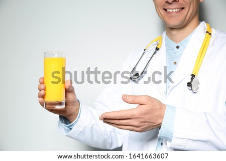 Nutritionist with glass of juice on light grey background, closeup