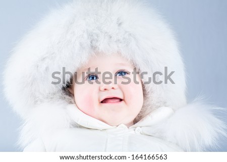 Happy laughing baby in a white winter jacket