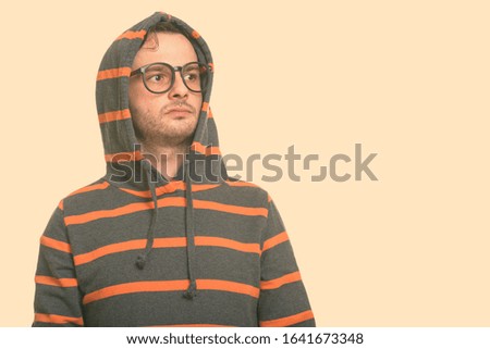 Studio shot of young man wearing hoodie while thinking