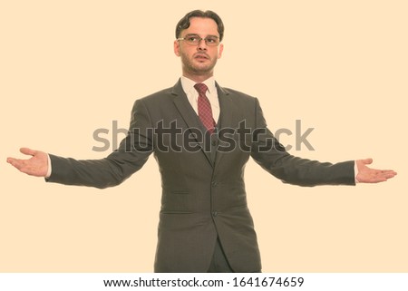 Studio shot of young businessman showing something with both hands raised