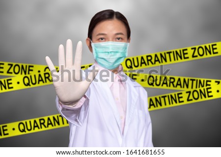 Asian female doctor wear a medical mask, raise hand for stop sign to do not enter quarantine area with yellow quarantine sign on the back, entrance is forbidden in quarantine zone. Royalty-Free Stock Photo #1641681655