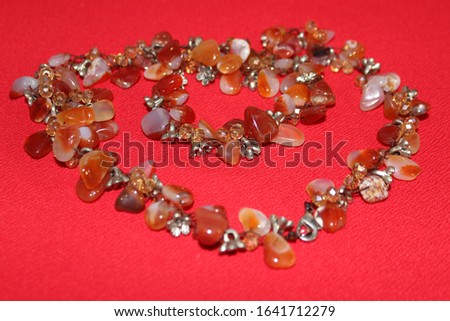 Amber beads on red background. Brown and beige beads. Brown beads with metal accents.
