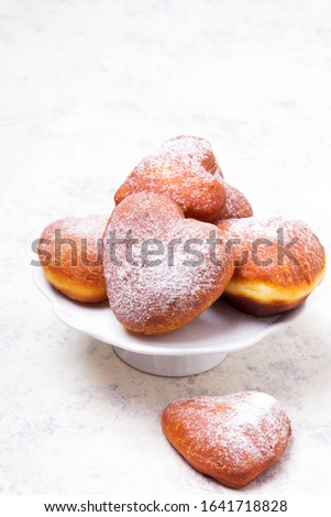 Homemade heart sheped donuts with powdered sugar on white background. Tasty doughnuts, copy space 