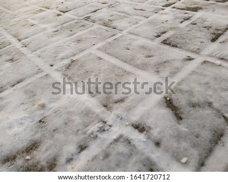 frozen sidewalk tiled with a layer of snow