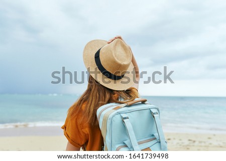 Woman with backpack hat sundress sea sand
