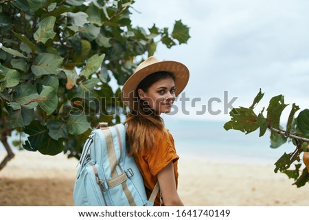 Woman on nature with a backpack on her back and a straw hat on her head