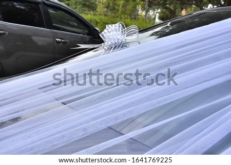White guipure ribbon with a bow on the hood of a black wedding card of the newlyweds, decor, background