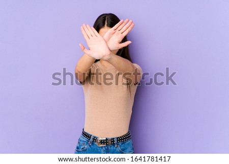 Young caucasian woman isolated on purple background keeping two arms crossed, denial concept.