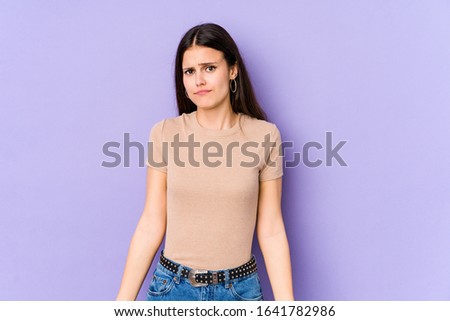Young caucasian woman isolated on purple background shrugs shoulders and open eyes confused.