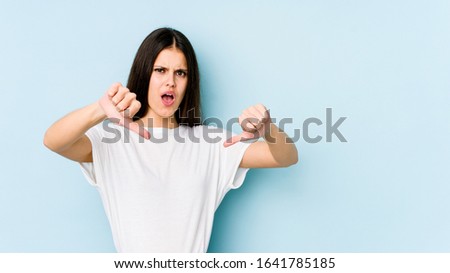 Young caucasian woman isolated on blue background showing thumb down and expressing dislike.