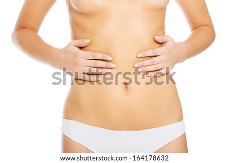 Slim and fit woman holds her hands on belly. Isolated on white. 