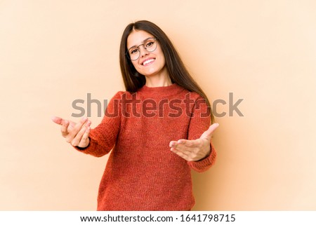 Young caucasian woman isolated on beige background showing a welcome expression.
