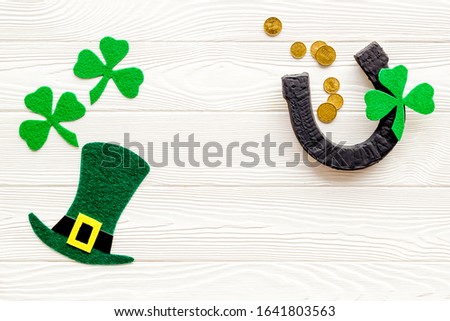 Composition for St. Patrick's Day.
Decorating paper with green clover or shamrocks, leprechaun hat and horseshoe.
White wooden background top view,flat lay, mockup