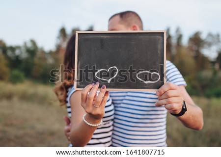 Lovers man and woman are holding a wooden sign for inscriptions and dates. 