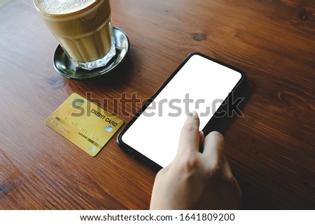 Close up of woman using phone,sending massages phone blank credit card texture on wood table within coffee shop.