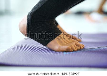 Close-up of woman legs on violet yoga or fitness mat indoor, doing yoga pose. Yoga Practice Exercise Class Concept.
