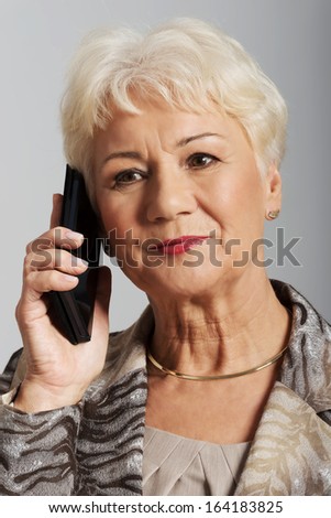 An old lady with mobile phone. On grey background. 