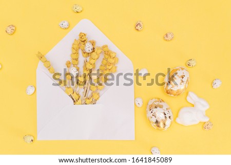 Golden chocolate Easter eggs and chocolate bunny with copy space on a yellow background.