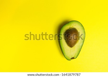 Green fresh avocado on isolated yellow background. Vitamin, vegan food concept