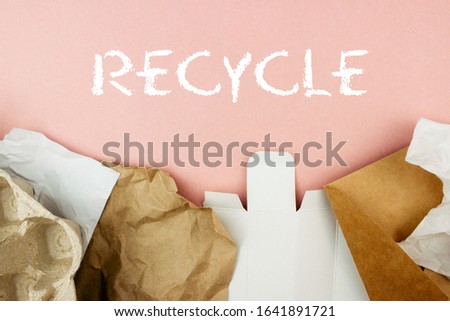 Paper garbage on pink background with recycle sign top view. Egg box, envelope, craft paper. Waste recycling, paper rubbish sorting, re-use of materials concept. Banner template. Stock photo.