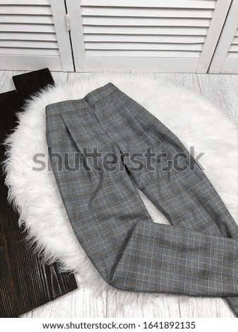 Gray female plaid pants close-up on a background of white fur and wood