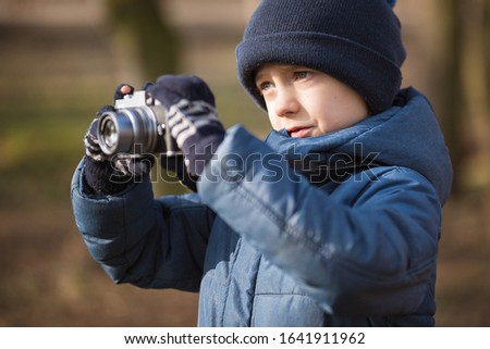 Young boy with camera taking pictures in the park