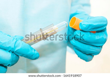 Hands of nurse in sterile gown and gloves take a thermometer out of case