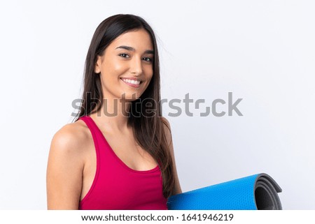 Young sport brunette woman over isolated white background with a mat and smiling