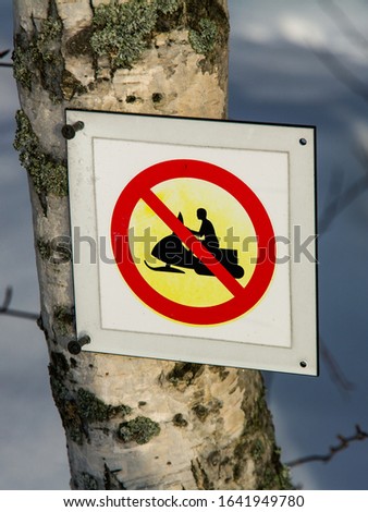 Snowmobiling is prohibited sign on birch trunk