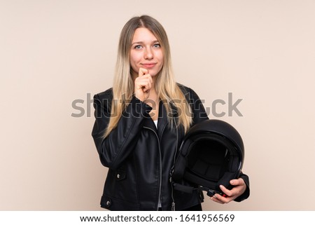 Young blonde woman with a motorcycle helmet over isolated background laughing