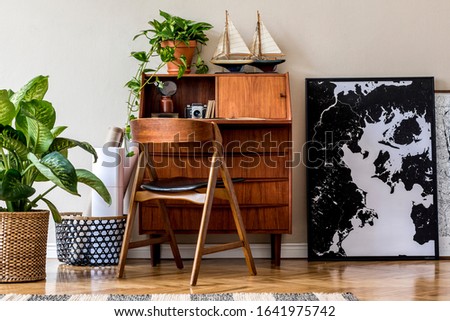Stylish and vintage interior design of living room with wooden retro commode, chair, tropical plants, ships and elegant personal accessories. Mock up poster frame on the floor. Template. Home decor.