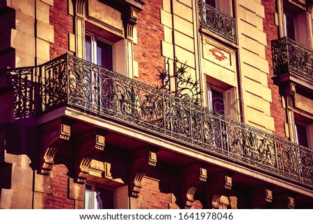 Typical Parisian architecture. Building fragment. Beautiful balcony with forging railing. Architectural detail. Paris, France.  Retro toned photo.