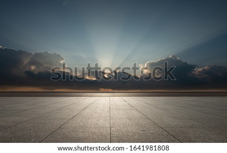 Under the setting sun, there is an empty square with no marble splicing. The tintar phenomenon formed by the sun through the clouds, jesus light