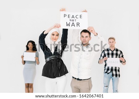Young people showing slogans for world peace, against war and terrorism. Multiethnical people, Arabic girl in hijab and Caucasian men, African American woman, holding no war slogans on white