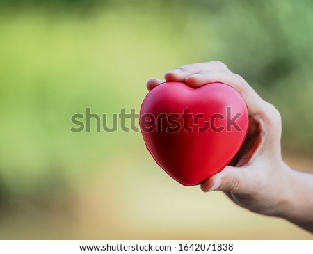 Close​ up​ to​ holding​ and​ show​ red​ heart​, abstract​ meaning for​ love​, take​ care with​ blurred​ background​ for​ valentine,falling​ in​ love​ and​ emotion​ concept