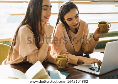 twins sisters notice something with note book. twins sisters drink a tea 
