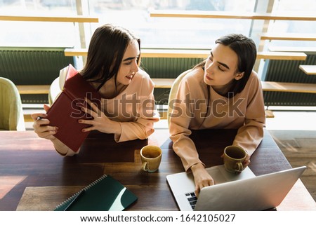 twins sisters notice something with note book. twins sisters drink a tea 