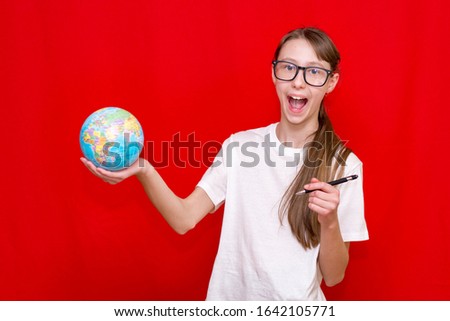 Front view of laughing  with braid schoolgirl is wearing glasses thinking something.Bright red studio background. Copy space.
