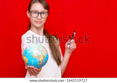 Dreamy young schoolgirl brunette in glasses.holds globe.Selective focus.Copy space. Studio shoot.
