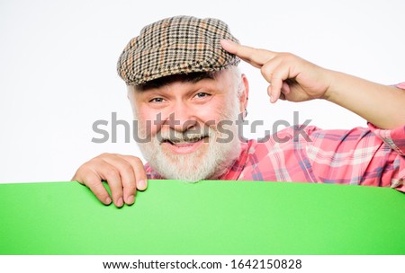 Pensioner grandfather in vintage hat hold poster information copy space. Event announcement. Announcement concept. Advertisement shop. Senior bearded man peek out of banner place announcement.
