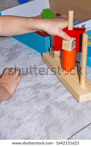 hands of a child who plays educational wooden toys with colored details